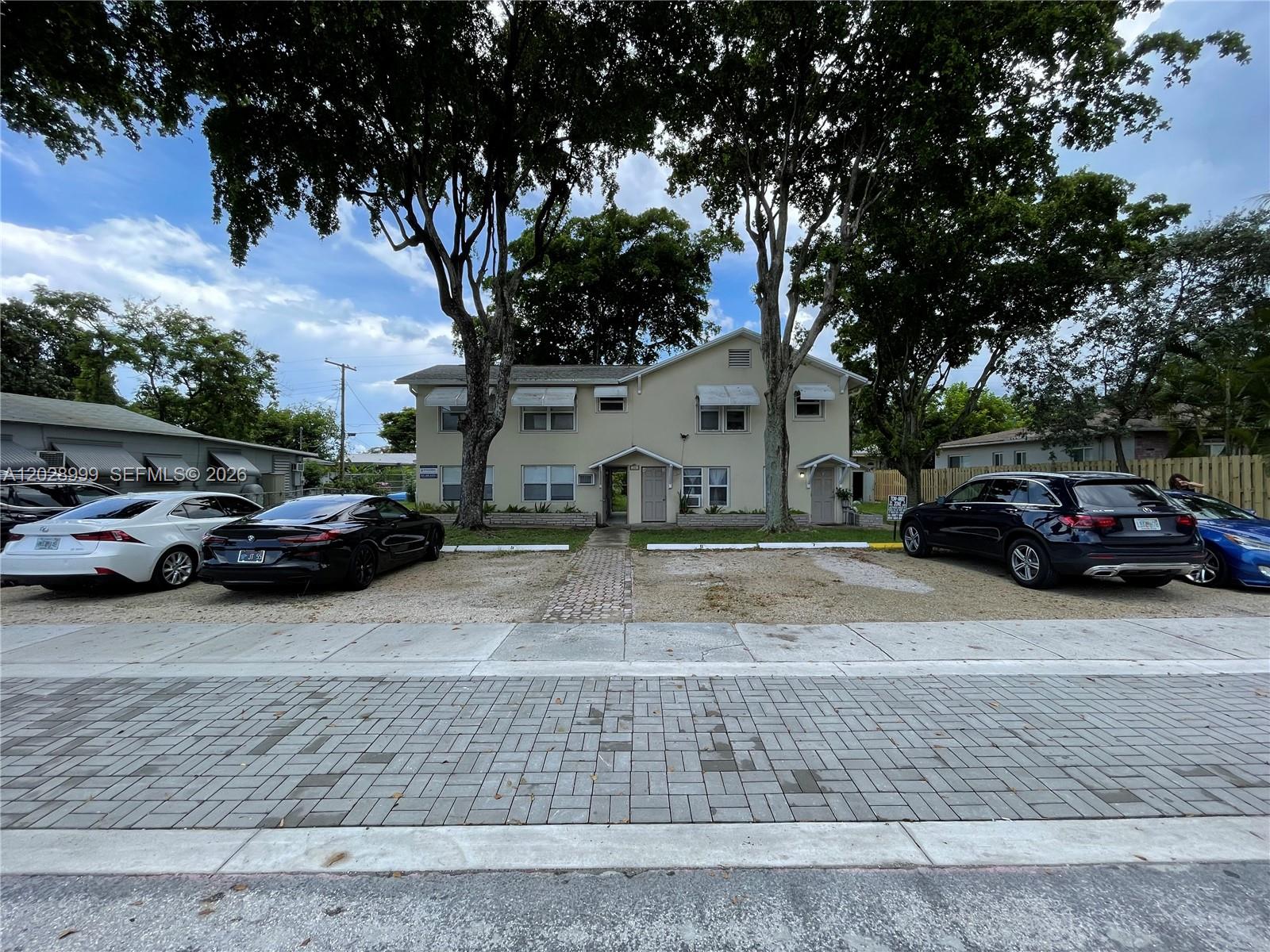 A two-story apartment building with a gravel parking lot and mature trees in front — 26 SE 13th Ter # 7, Dania Beach FL 33004, DANIA BEACH, FL