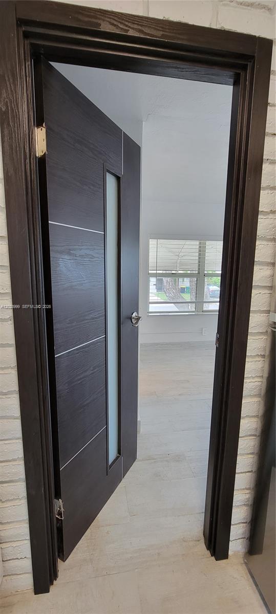 A dark wood door with a frosted glass panel opens into a room with light-colored flooring — 26 SE 13th Ter # 7, Dania Beach FL 33004, DANIA BEACH, FL