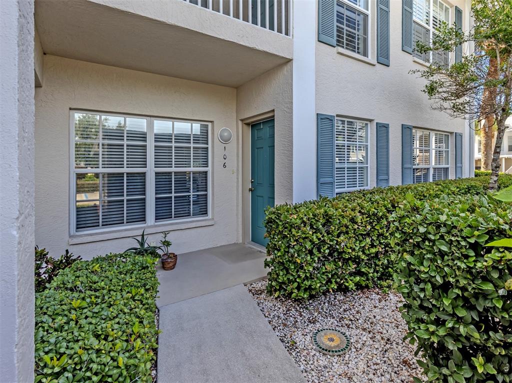 A teal front door with the number 106 sits beside a window on a stucco building — 872 SARANAC LAKE DRIVE UNIT 106, VENICE, FL