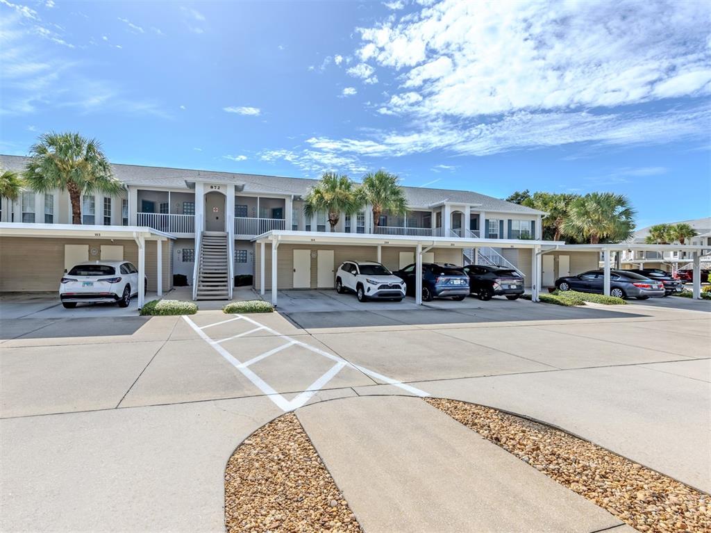 A two-story apartment building with covered parking spaces and several parked cars — 872 SARANAC LAKE DRIVE UNIT 106, VENICE, FL