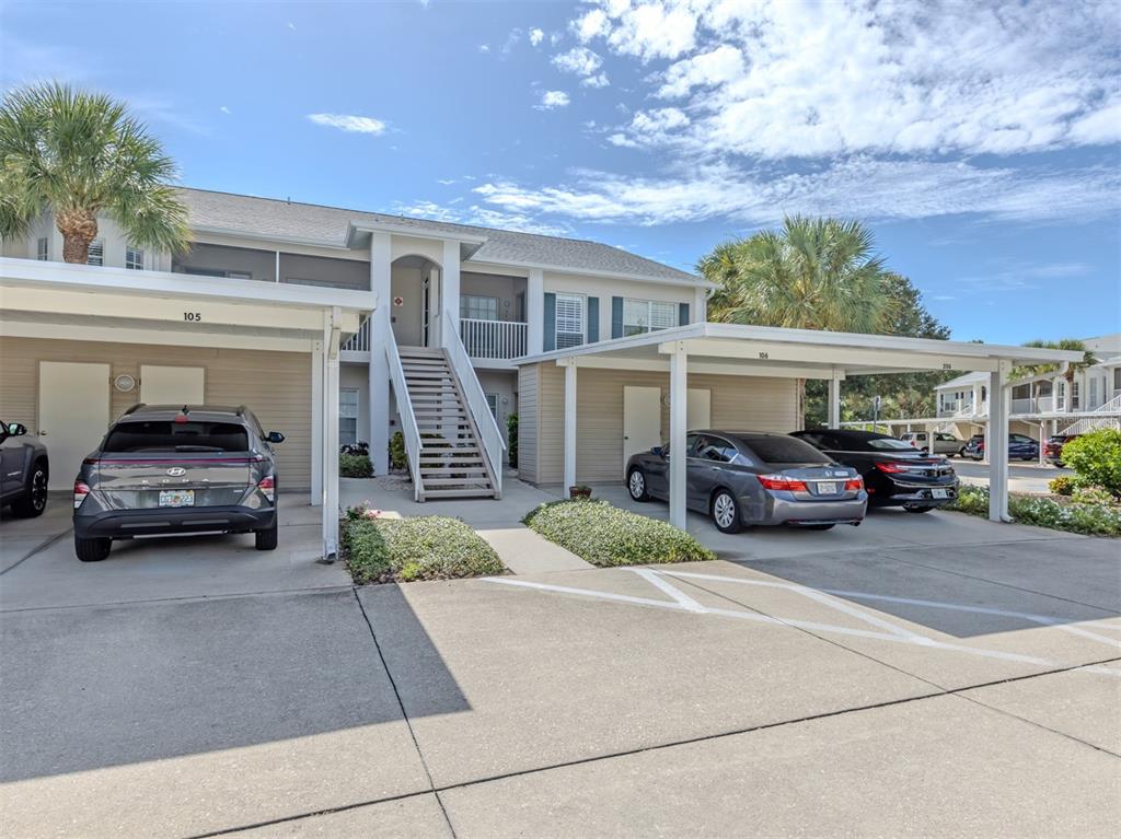 A two-story apartment building features covered parking spaces and an exterior staircase — 872 SARANAC LAKE DRIVE UNIT 106, VENICE, FL