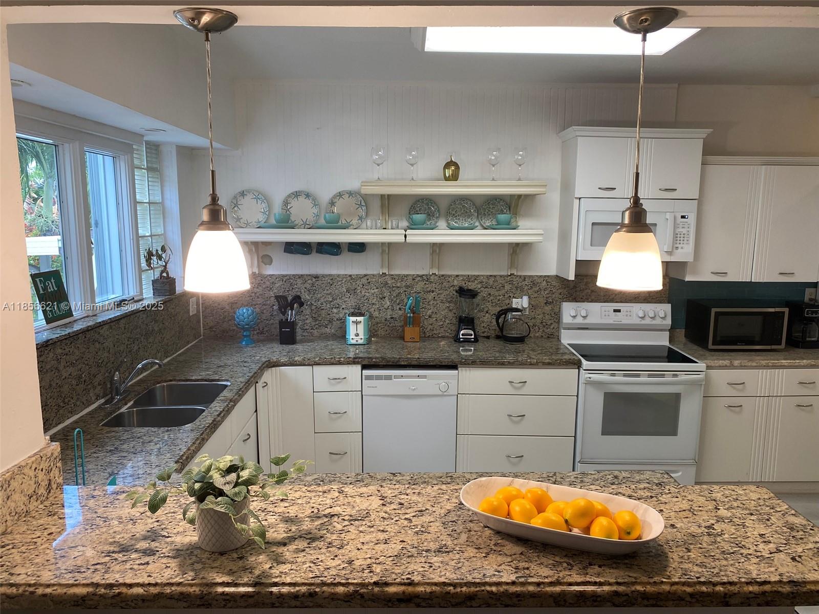 A kitchen features white cabinets, granite countertops, two pendant lights, and a white stove — 701 Hollywood Blvd # 701, Hollywood FL 33019, HOLLYWOOD, FL