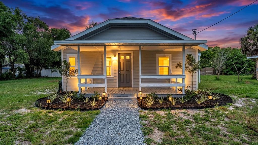 A small, single-story house with a front porch and gravel walkway at sunset — 820 26TH STREET NW, WINTER HAVEN, FL