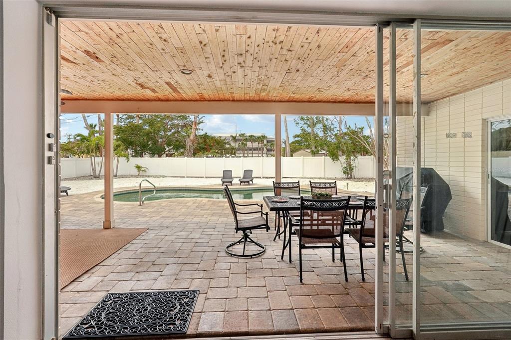 A covered patio with a dining set overlooks a swimming pool and a fenced yard — 55 N WASHINGTON DRIVE, SARASOTA, FL