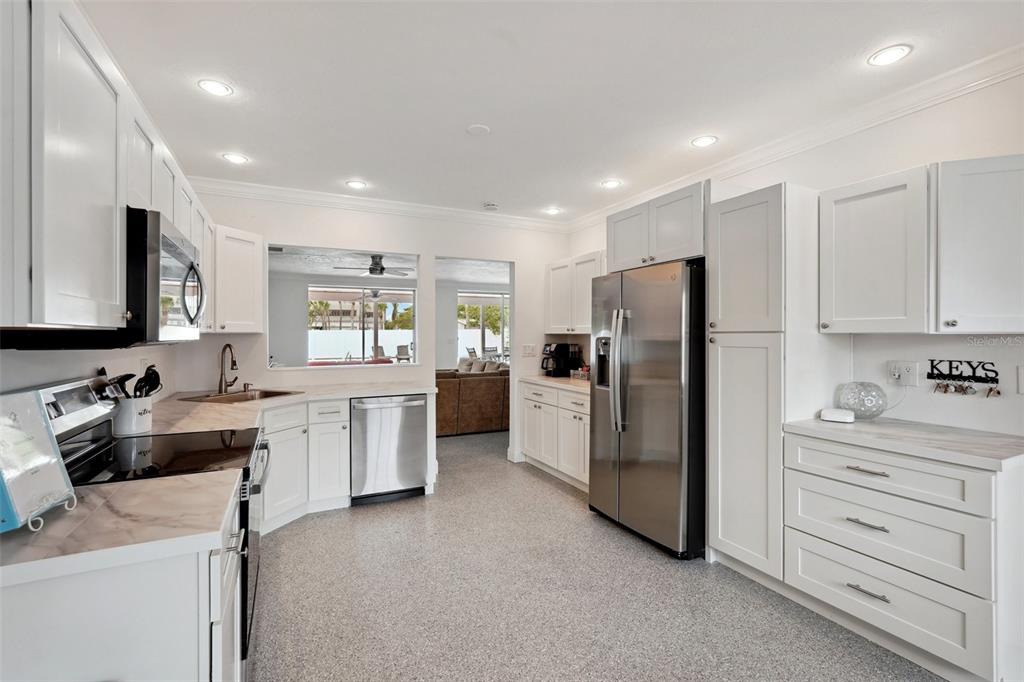 A white kitchen with stainless steel appliances, speckled flooring, and a pass-through window to outdoors — 55 N WASHINGTON DRIVE, SARASOTA, FL