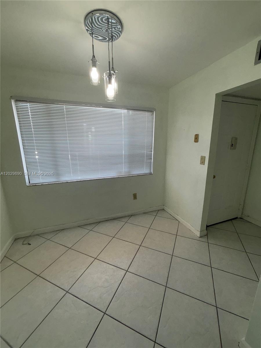 This room features white tiled floors, a large window with blinds, and a hanging light fixture — TAMARAC, FL