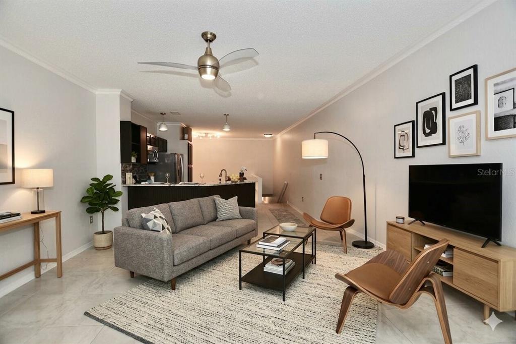 A living room with a gray sofa, coffee table, television, and an open kitchen area — 858 NORMANDY TRACE ROAD, TAMPA, FL