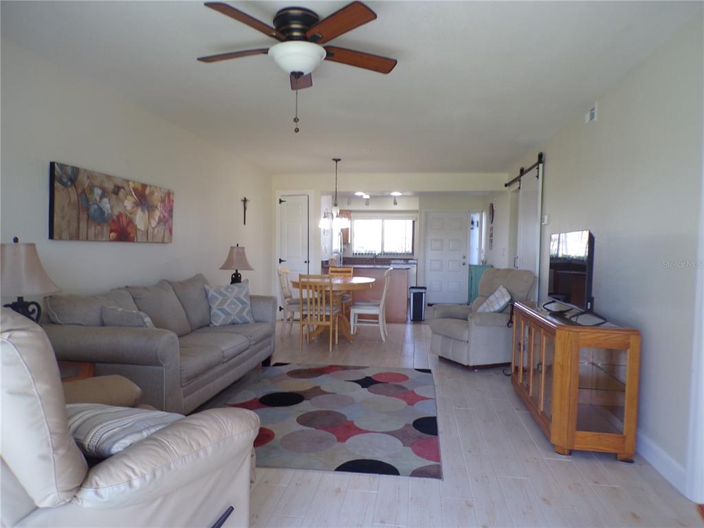 A living room with a sofa, armchairs, dining area, and light-colored tile flooring — 1356 RIO DE JANEIRO AVENUE UNIT 108, PUNTA GORDA, FL