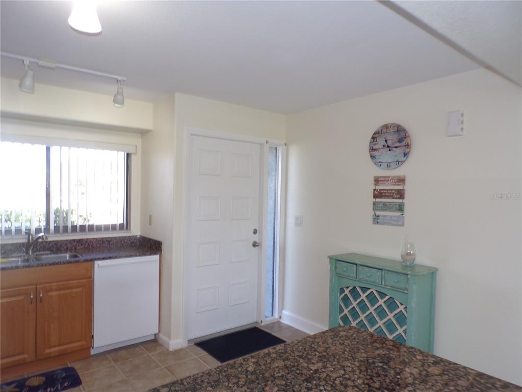 A kitchen features a white door, a granite countertop, and a light blue wine rack — 1356 RIO DE JANEIRO AVENUE UNIT 108, PUNTA GORDA, FL