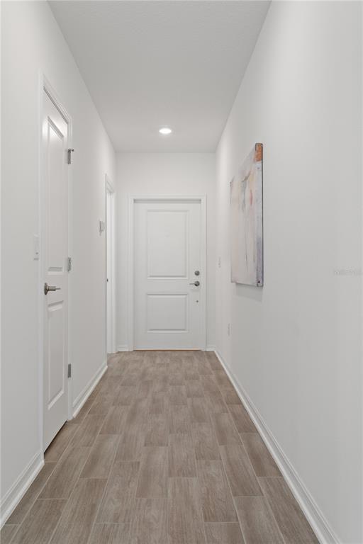 A hallway with white walls, wood-look tile flooring, and two white interior doors — 1243 SAND TRAP COURT, DAYTONA BEACH, FL