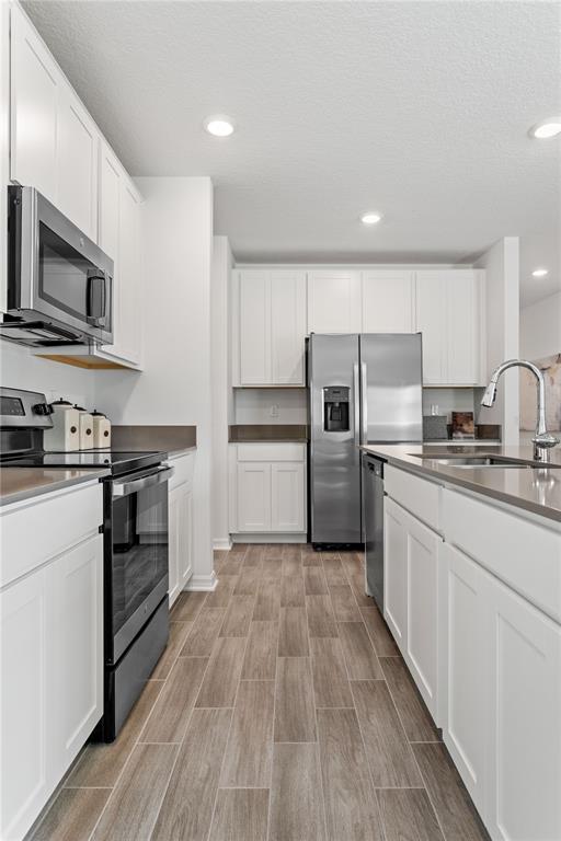 A kitchen features white cabinets, stainless steel appliances, quartz countertops, and wood-look tile flooring — 1243 SAND TRAP COURT, DAYTONA BEACH, FL