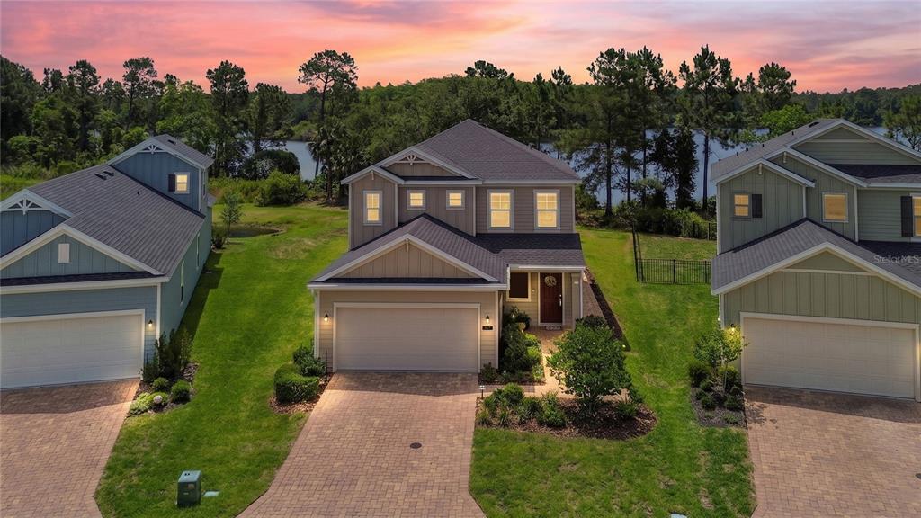 An aerial view of a two-story suburban house with a paved driveway and lake view — 367 LAKE SINCLAIR STREET, ST AUGUSTINE, FL