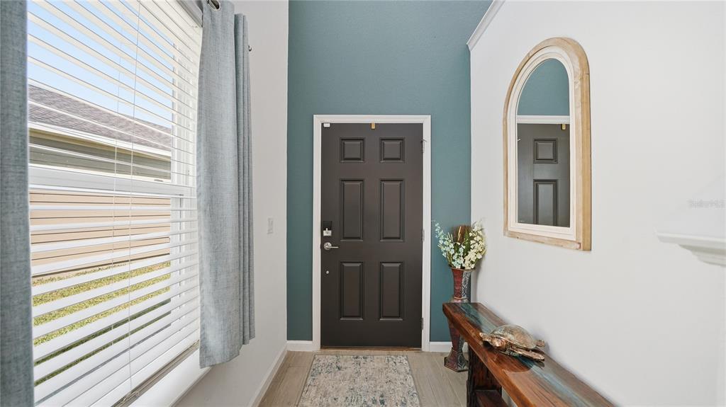An entryway features a dark brown door, a teal accent wall, and a wooden console table — 367 LAKE SINCLAIR STREET, ST AUGUSTINE, FL