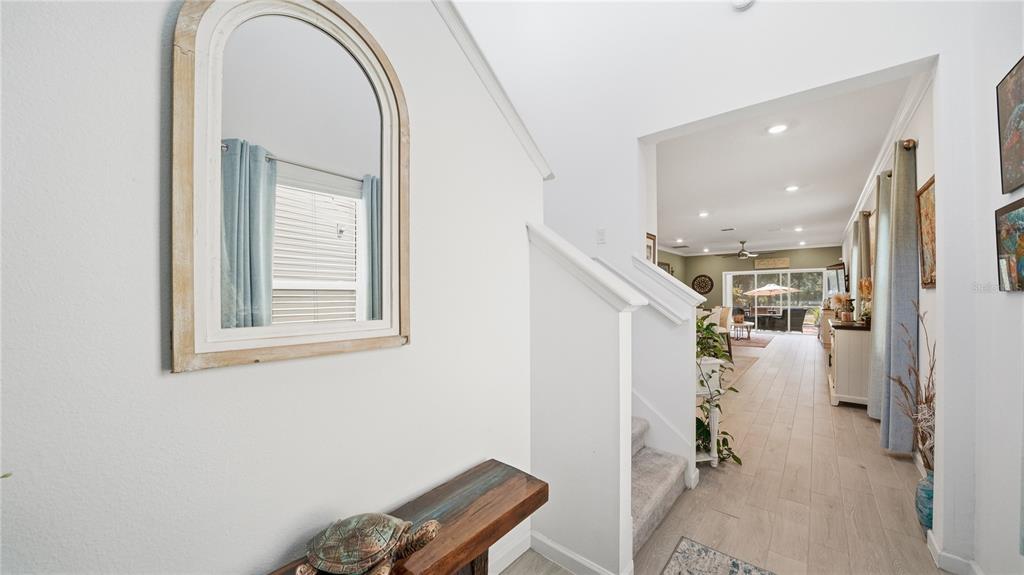 A foyer with a wooden console table, arched mirror, and stairs leading to an open living area — 367 LAKE SINCLAIR STREET, ST AUGUSTINE, FL