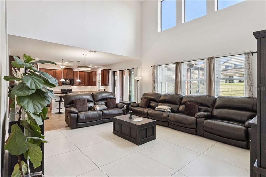 A spacious living room with high ceilings, tile floors, and two dark leather sofas — 3979 SUNSET LAKE DRIVE, LAKELAND, FL