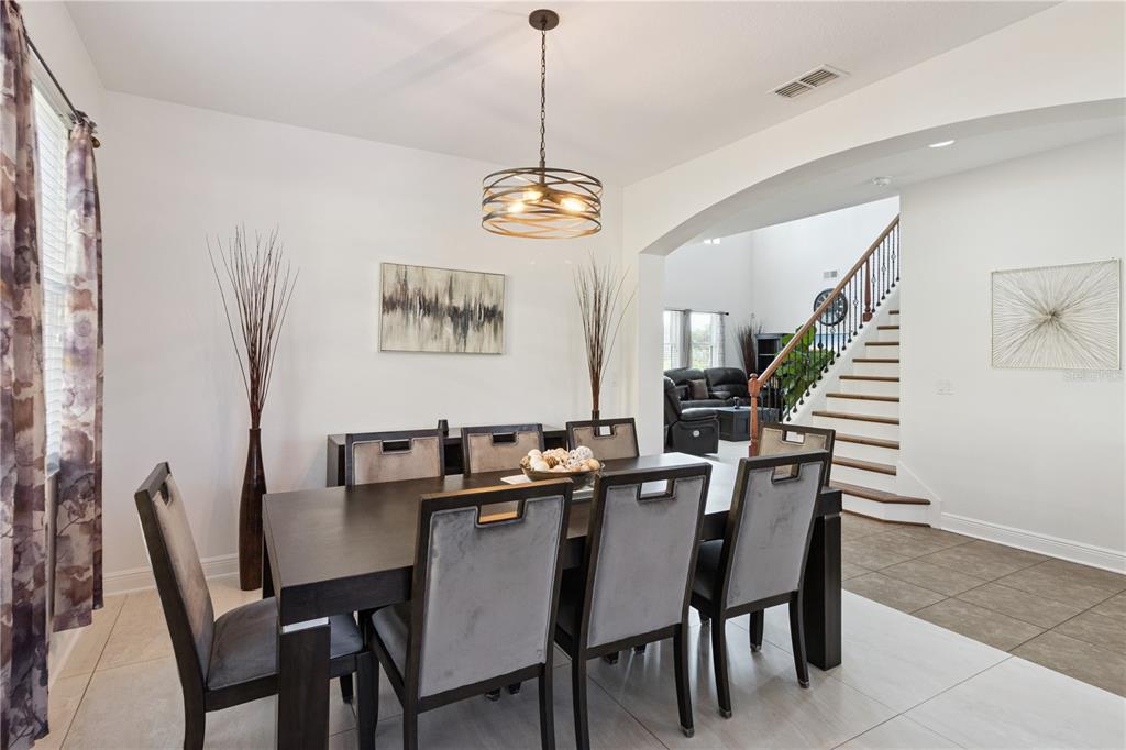 A dining room with a dark wood table, gray upholstered chairs, and a modern chandelier — 3979 SUNSET LAKE DRIVE, LAKELAND, FL