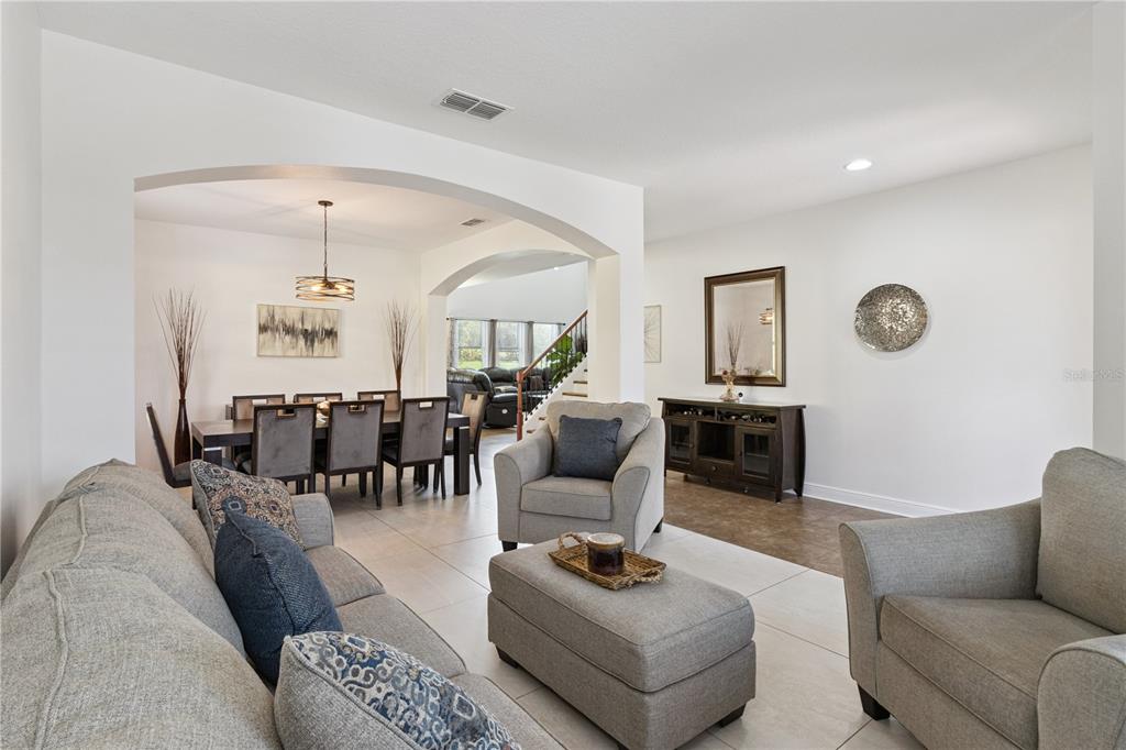 A living room with light tile flooring opens into a dining area with arched doorways — 3979 SUNSET LAKE DRIVE, LAKELAND, FL