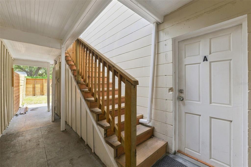 An outdoor staircase with a wooden railing leads to an upper level beside a door — 6027 1ST AVENUE N UNIT B, ST PETERSBURG, FL