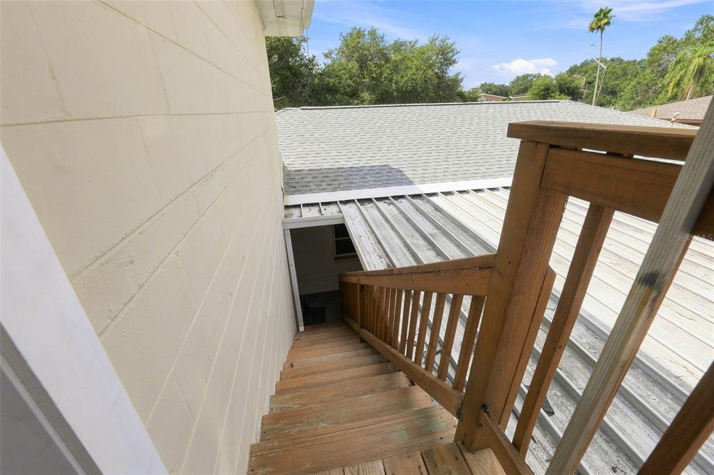 An outdoor wooden staircase leads down to a covered patio area next to a building — 6027 1ST AVENUE N UNIT B, ST PETERSBURG, FL