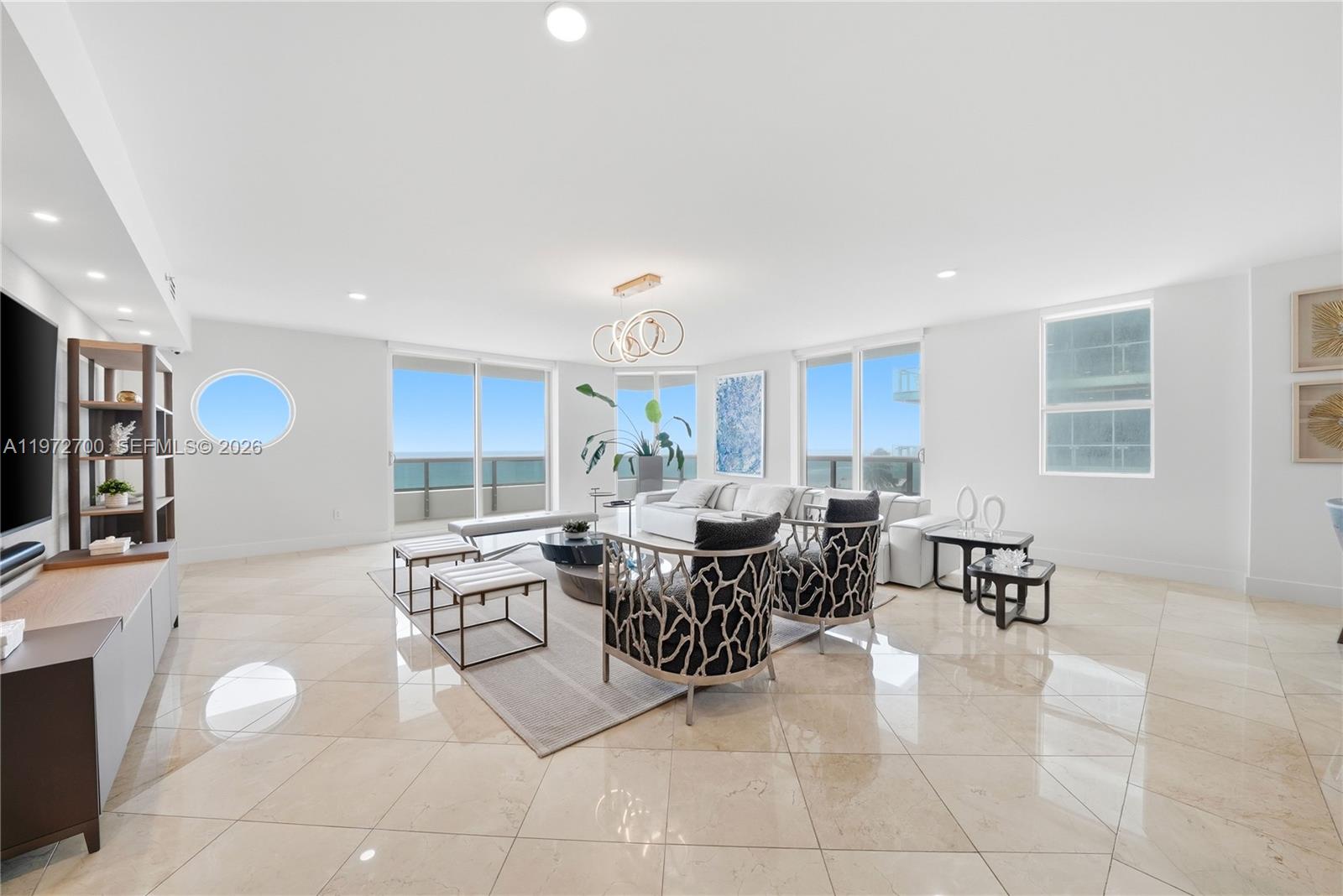 A bright living room features white walls, tile flooring, modern furniture, and ocean views — 5801 Collins Ave # 700, Miami Beach FL 33140, MIAMI BEACH, FL