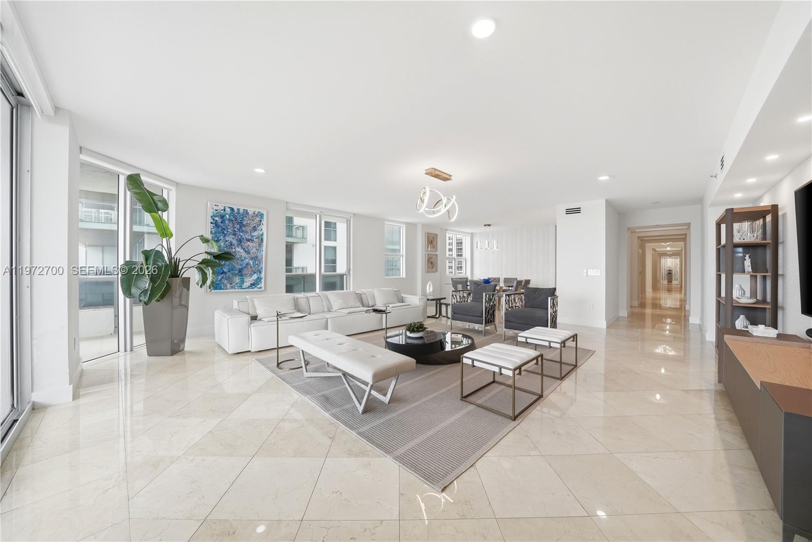 A bright, open-concept living room features white tile floors, a large sectional, and modern decor — 5801 Collins Ave # 700, Miami Beach FL 33140, MIAMI BEACH, FL