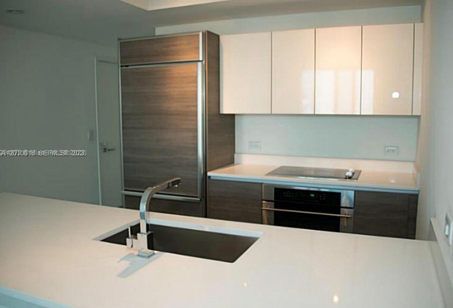 A modern kitchen features white countertops, dark wood cabinetry, and stainless steel appliances — 1100 S Miami Ave # 2407, Miami FL 33130, MIAMI, FL