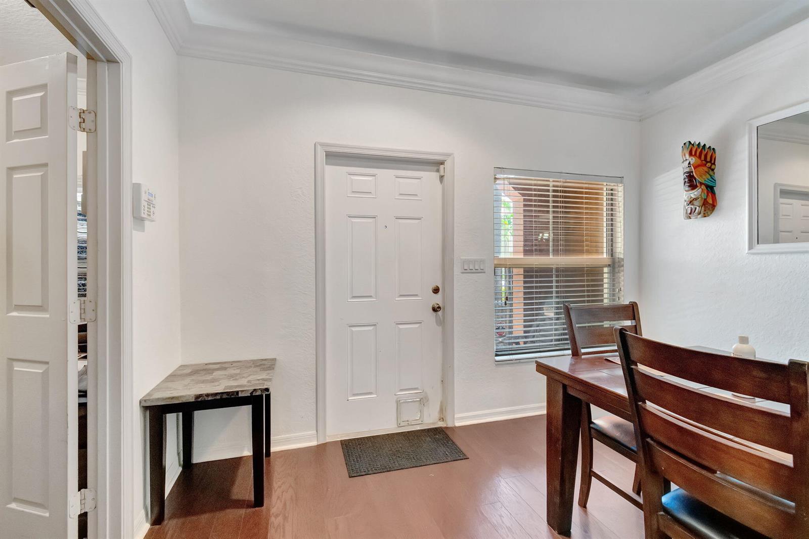 A dining area features white walls, wood flooring, a door with a pet flap, and furniture — 103 Monterey Bay Drive, Boynton Beach FL 33426, BOYNTON BEACH, FL