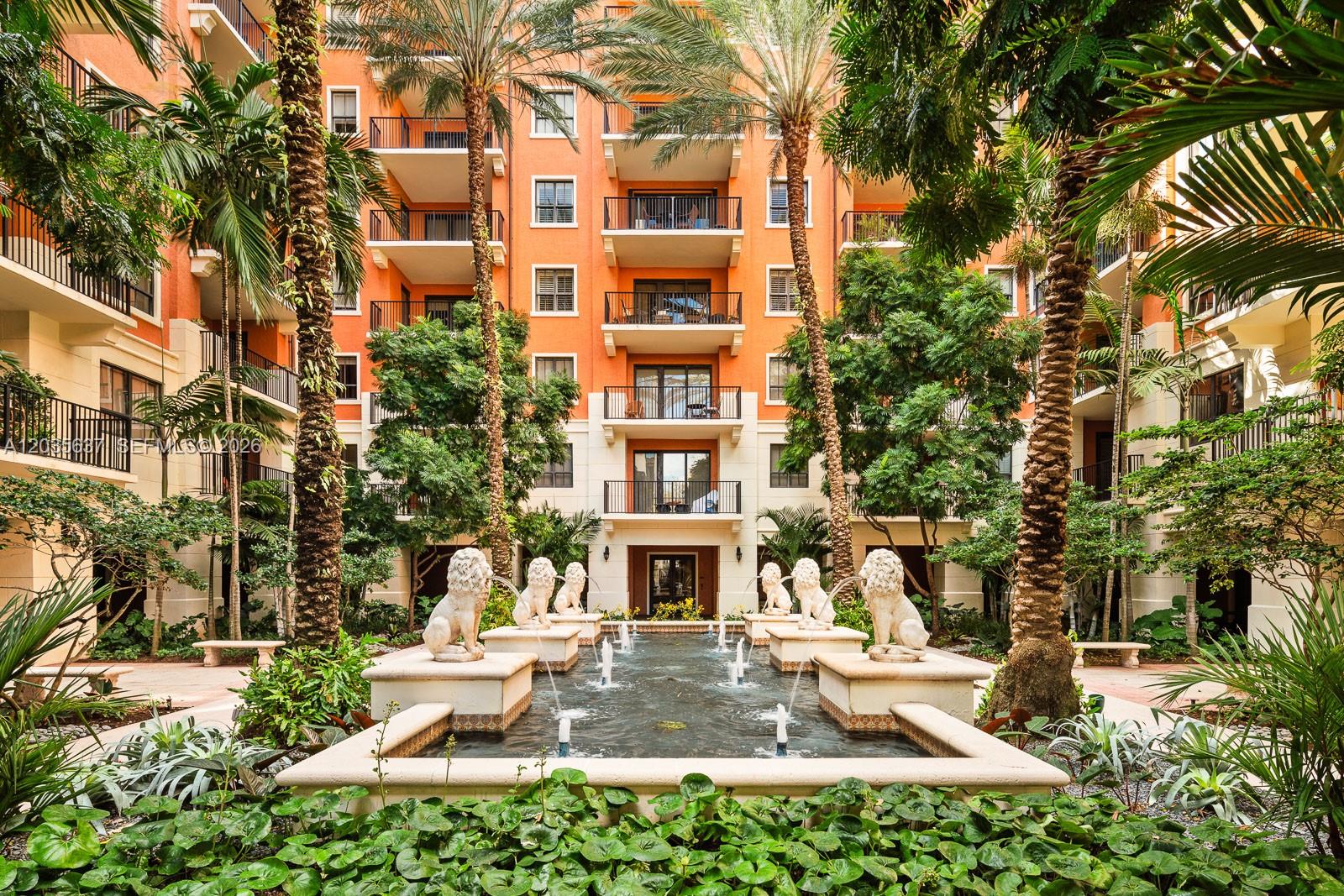 A courtyard features a tiered stone fountain with lion statues surrounded by palm trees and apartments — 100 Andalusia Ave # 402, Coral Gables FL 33134, CORAL GABLES, FL