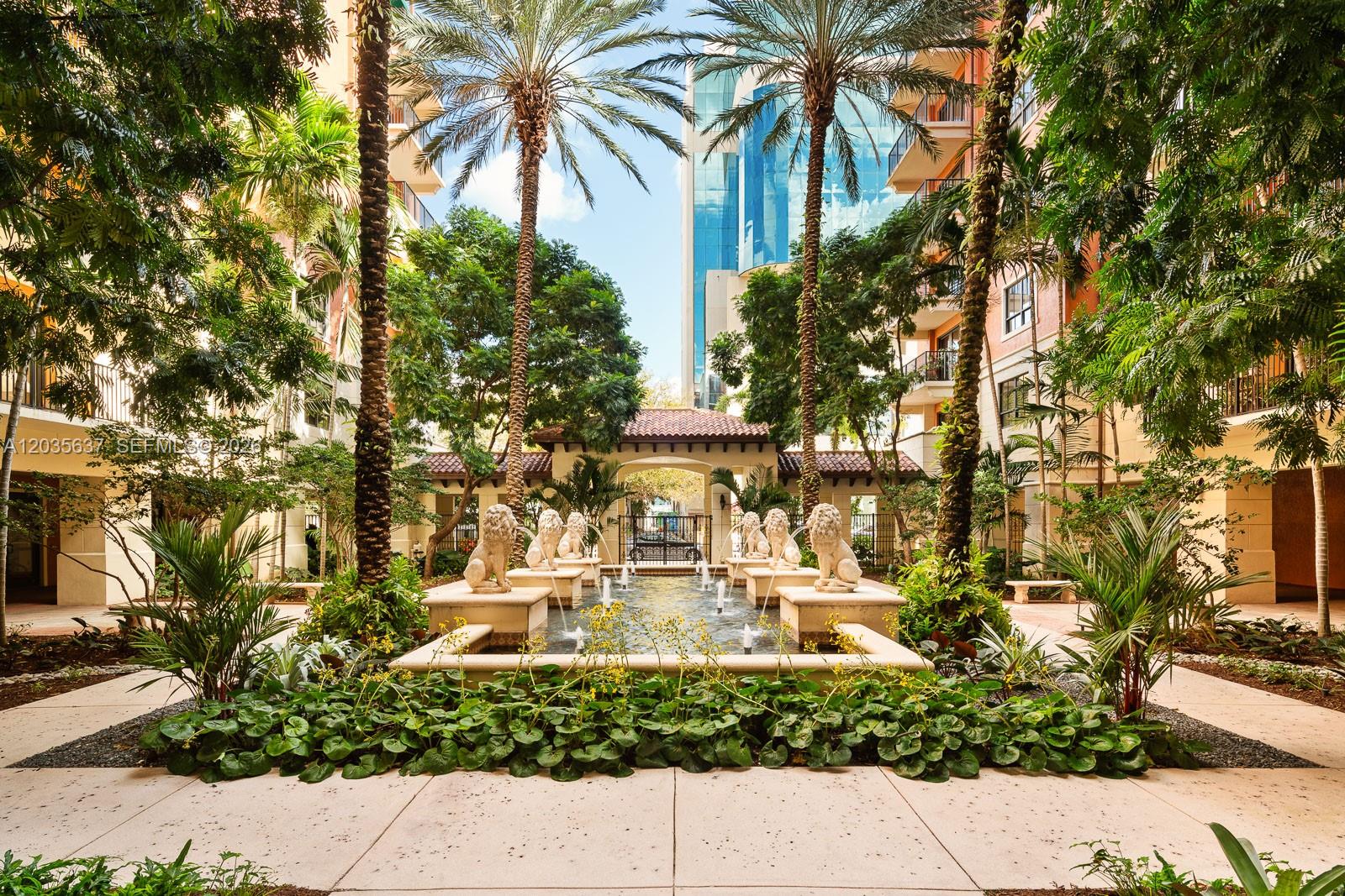 A courtyard features a central fountain with lion statues surrounded by palm trees and buildings — 100 Andalusia Ave # 402, Coral Gables FL 33134, CORAL GABLES, FL