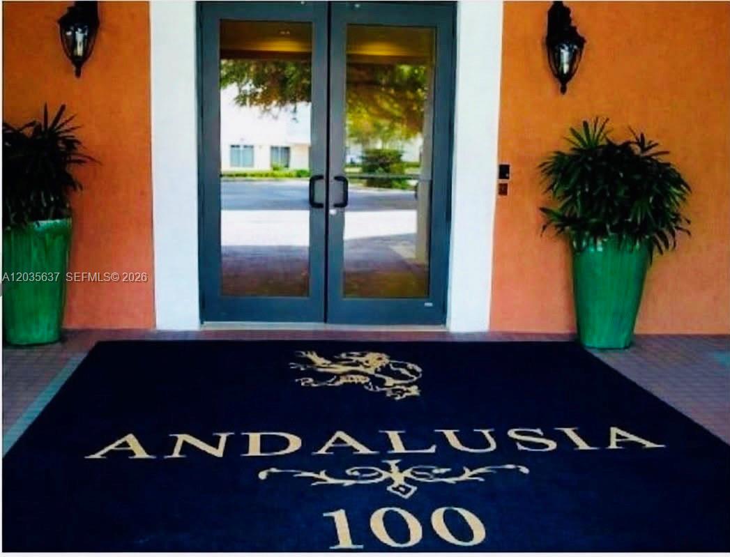 A dark blue mat with the name Andalusia 100 sits before a glass double door entrance — 100 Andalusia Ave # 402, Coral Gables FL 33134, CORAL GABLES, FL