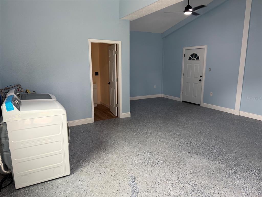 A garage with light blue walls, a speckled epoxy floor, a ceiling fan, and a washer — 37631 KOSSIK ROAD, ZEPHYRHILLS, FL