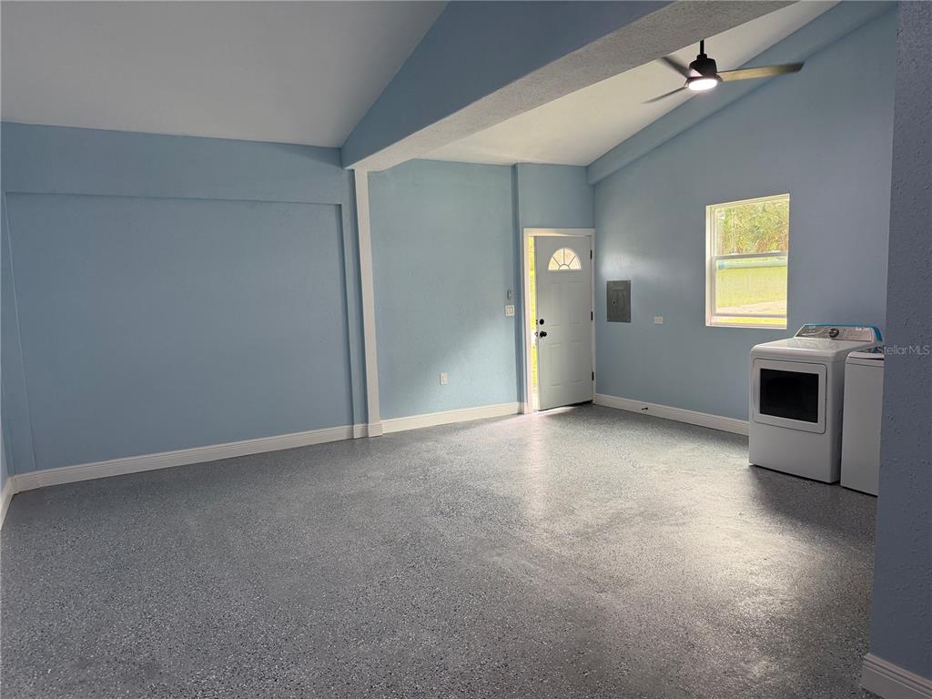 A garage with light blue walls, a speckled epoxy floor, and a white laundry appliance — 37631 KOSSIK ROAD, ZEPHYRHILLS, FL