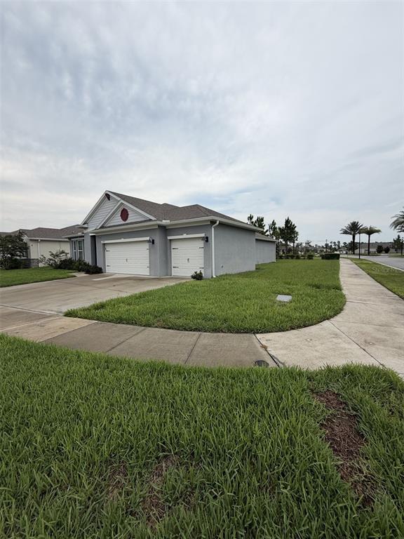 A gray single-story house with a three-car garage and a lawn on a corner lot — 6799 SARUS CRANE POINT, ST CLOUD, FL
