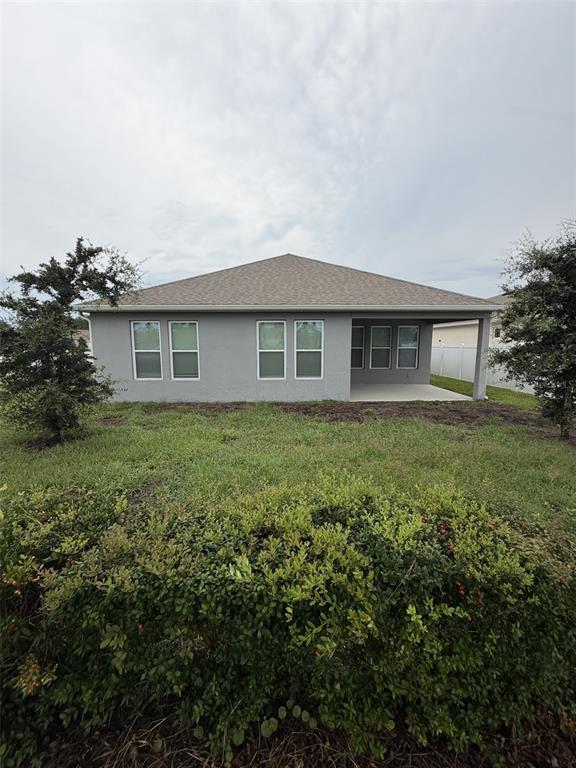 The rear exterior of a gray, single-story house features a covered patio and lawn — 6799 SARUS CRANE POINT, ST CLOUD, FL