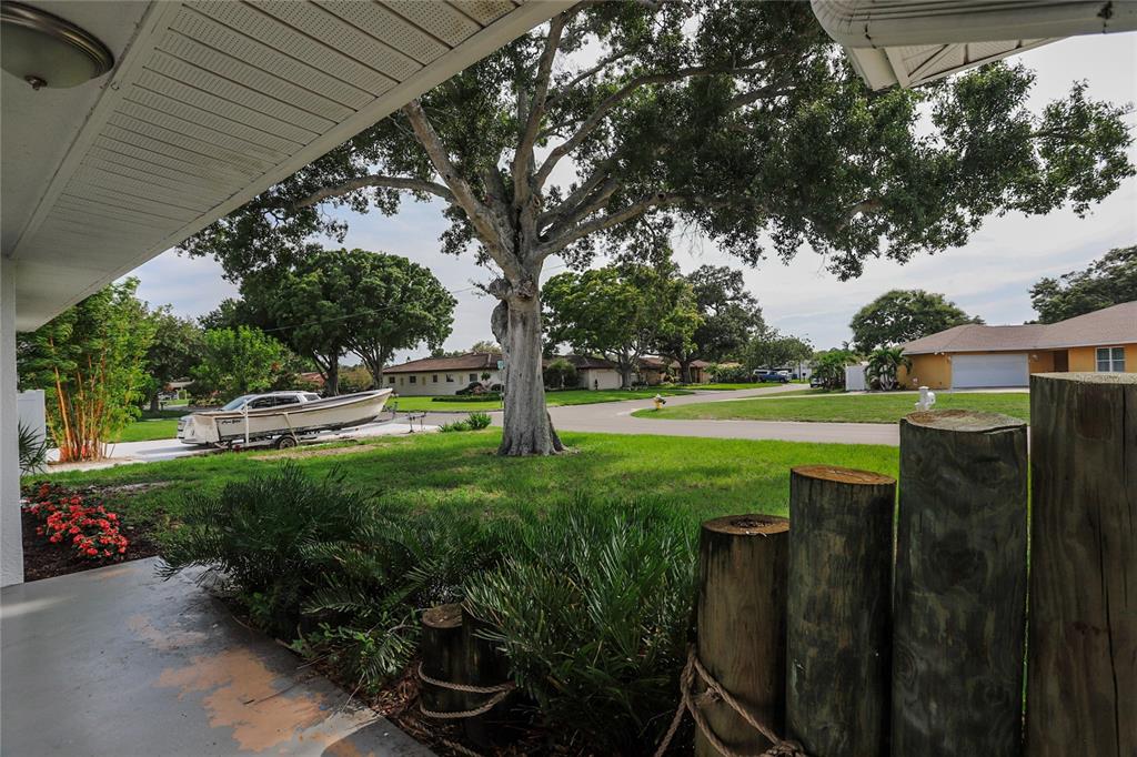 A view from a covered porch looking out toward a lawn, large tree, and boat — 10011 110TH STREET, SEMINOLE, FL