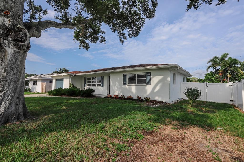 A single-story white house with a large tree in the front yard and white fencing — 10011 110TH STREET, SEMINOLE, FL