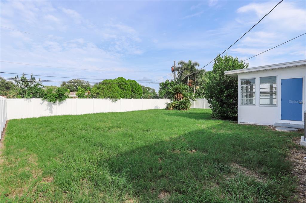 A grassy backyard features a white vinyl fence, a palm tree, and a white house — 10011 110TH STREET, SEMINOLE, FL