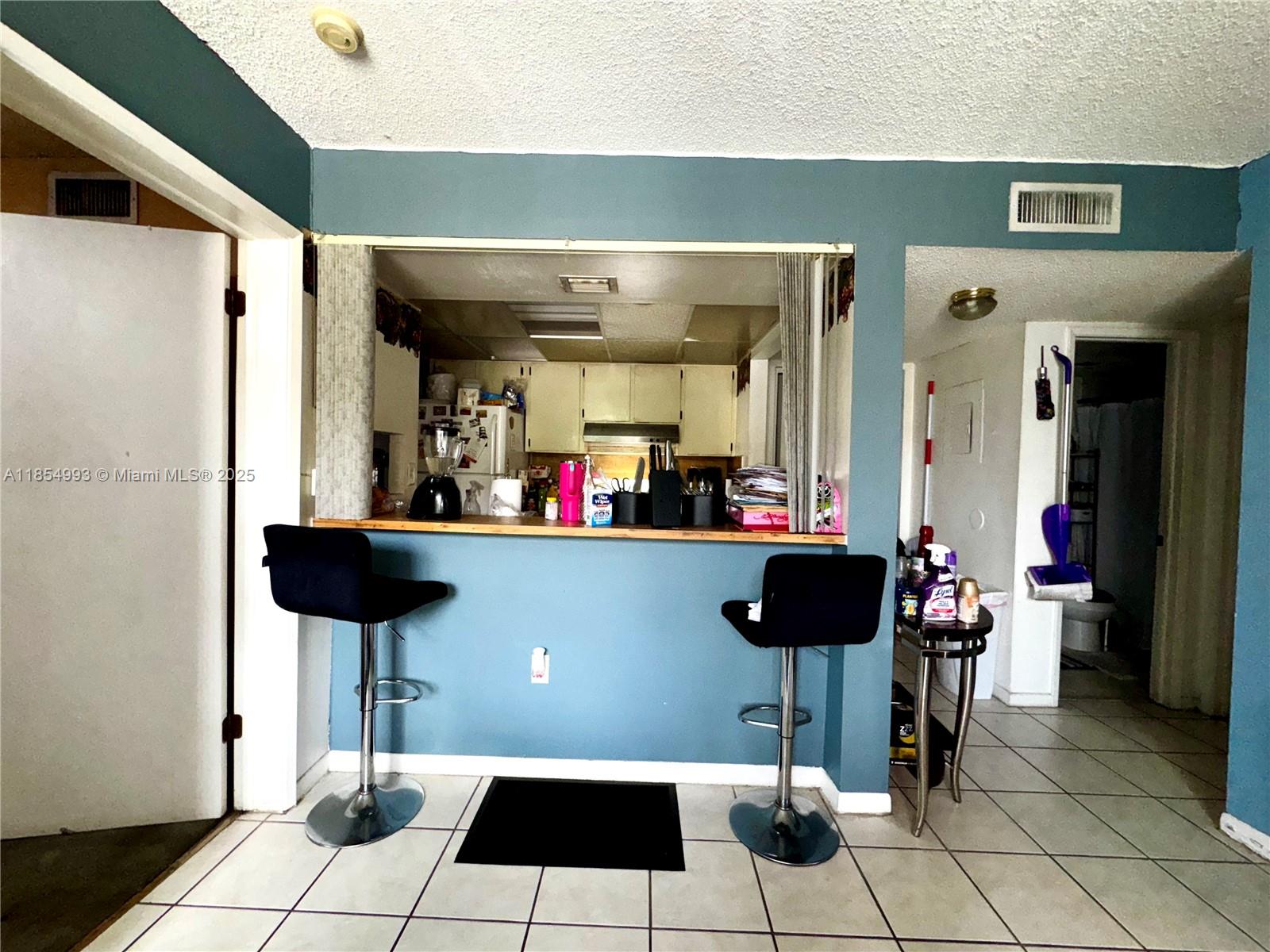 A kitchen pass-through window with a breakfast bar and two black stools — 7165 NW 186th St # A211, Hialeah FL 33015, HIALEAH, FL