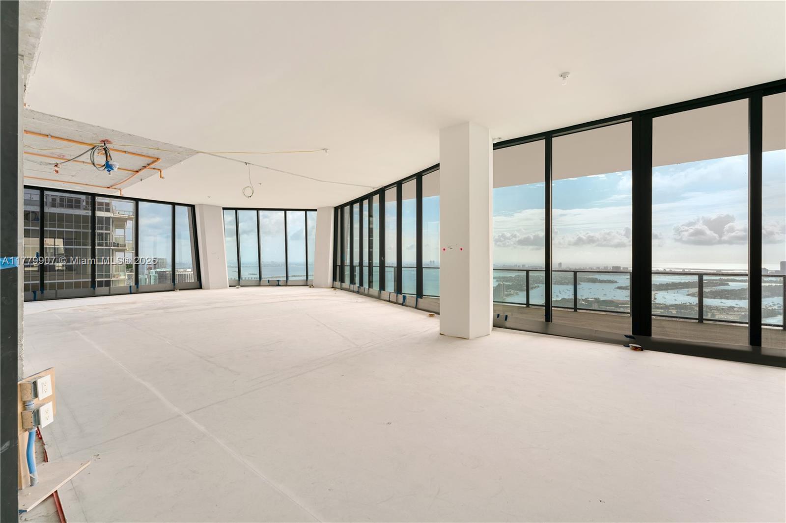 An unfinished high-rise apartment interior features floor-to-ceiling windows with expansive water and city views — 1000 Biscayne Blvd # 5801, Miami FL 33132, MIAMI, FL
