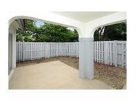 A covered concrete patio overlooks a small backyard enclosed by a white wooden fence — 1371 Cottonwood Circle, Weston FL 33326, WESTON, FL