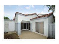 A white stucco house exterior features a covered patio, sliding glass doors, and tiled roof — 1371 Cottonwood Circle, Weston FL 33326, WESTON, FL