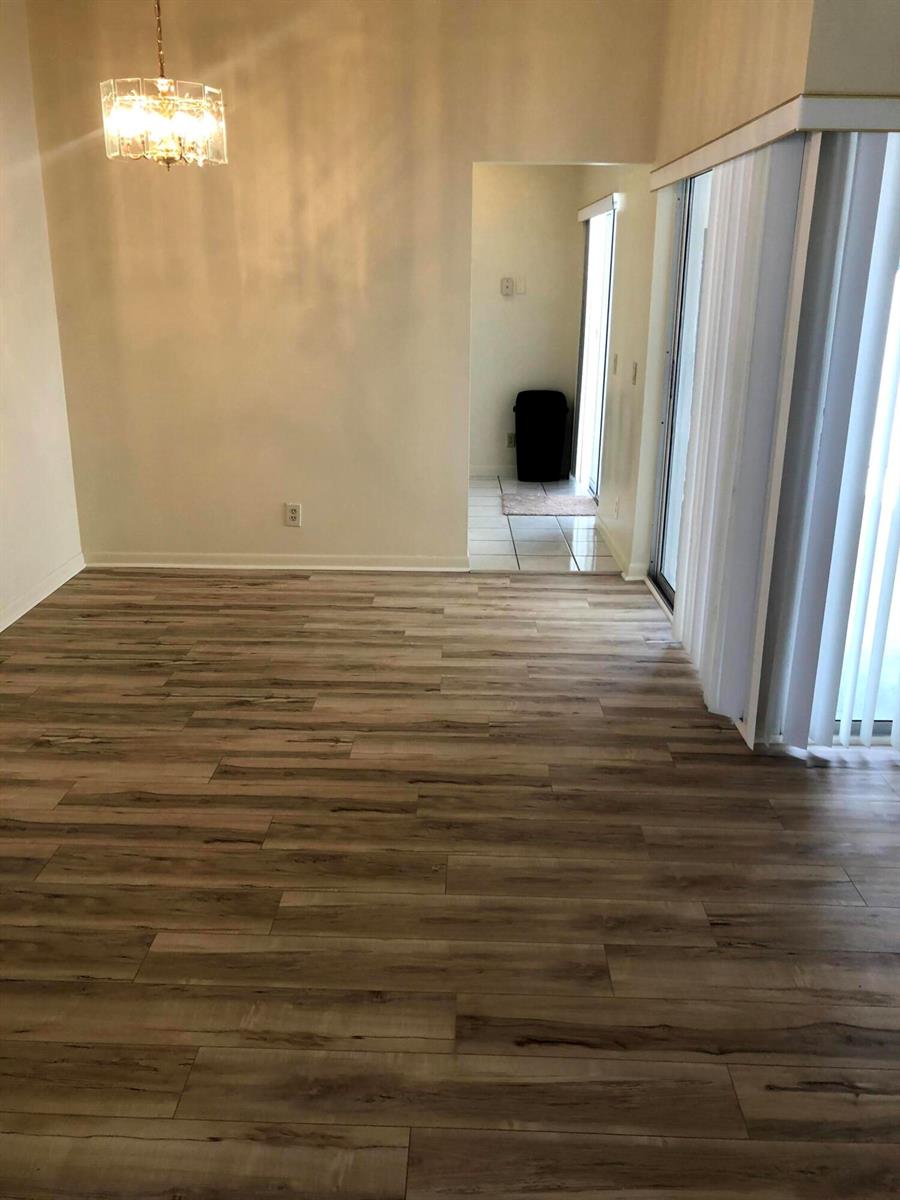 A dining area with wood-look laminate flooring, a chandelier, and a doorway leading outside — 1371 Cottonwood Circle, Weston FL 33326, WESTON, FL