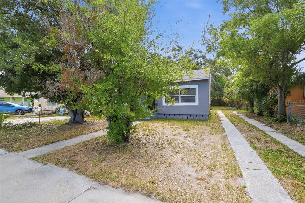 A gray single-story house sits behind a tree with a concrete driveway in the front — 2610 DR MARTIN LUTHER KING JR STREET S, ST PETERSBURG, FL