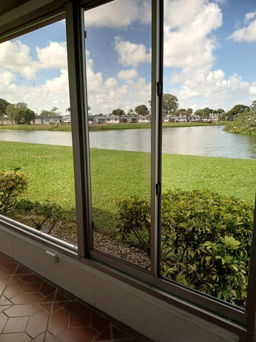 A view of a lake and neighborhood from a tiled, screened-in porch — 92 Seville, Delray Beach FL 33446, DELRAY BEACH, FL