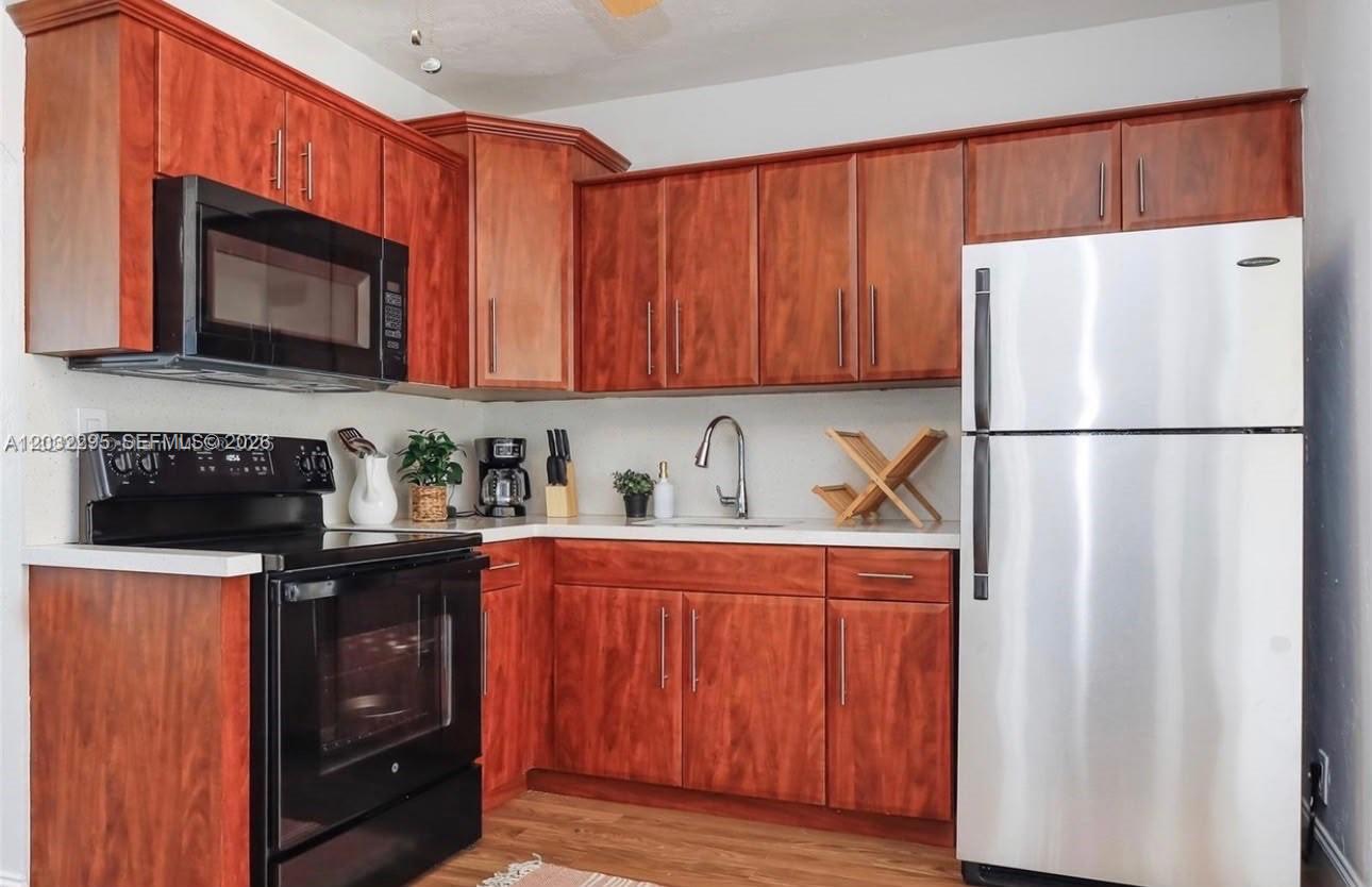 A kitchen features cherry-toned wood cabinets, stainless steel appliances, and white countertops — 2740 Dewey St, Hollywood FL 33020, HOLLYWOOD, FL