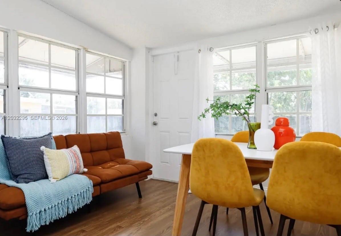 A sunroom features a brown sofa, a dining table with yellow chairs, and large windows — 2740 Dewey St, Hollywood FL 33020, HOLLYWOOD, FL