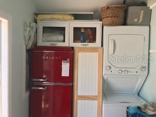 A small laundry area features a red refrigerator, a white cabinet, and a stacked washer-dryer — 20285 US HIGHWAY 27 UNIT 21, CLERMONT, FL