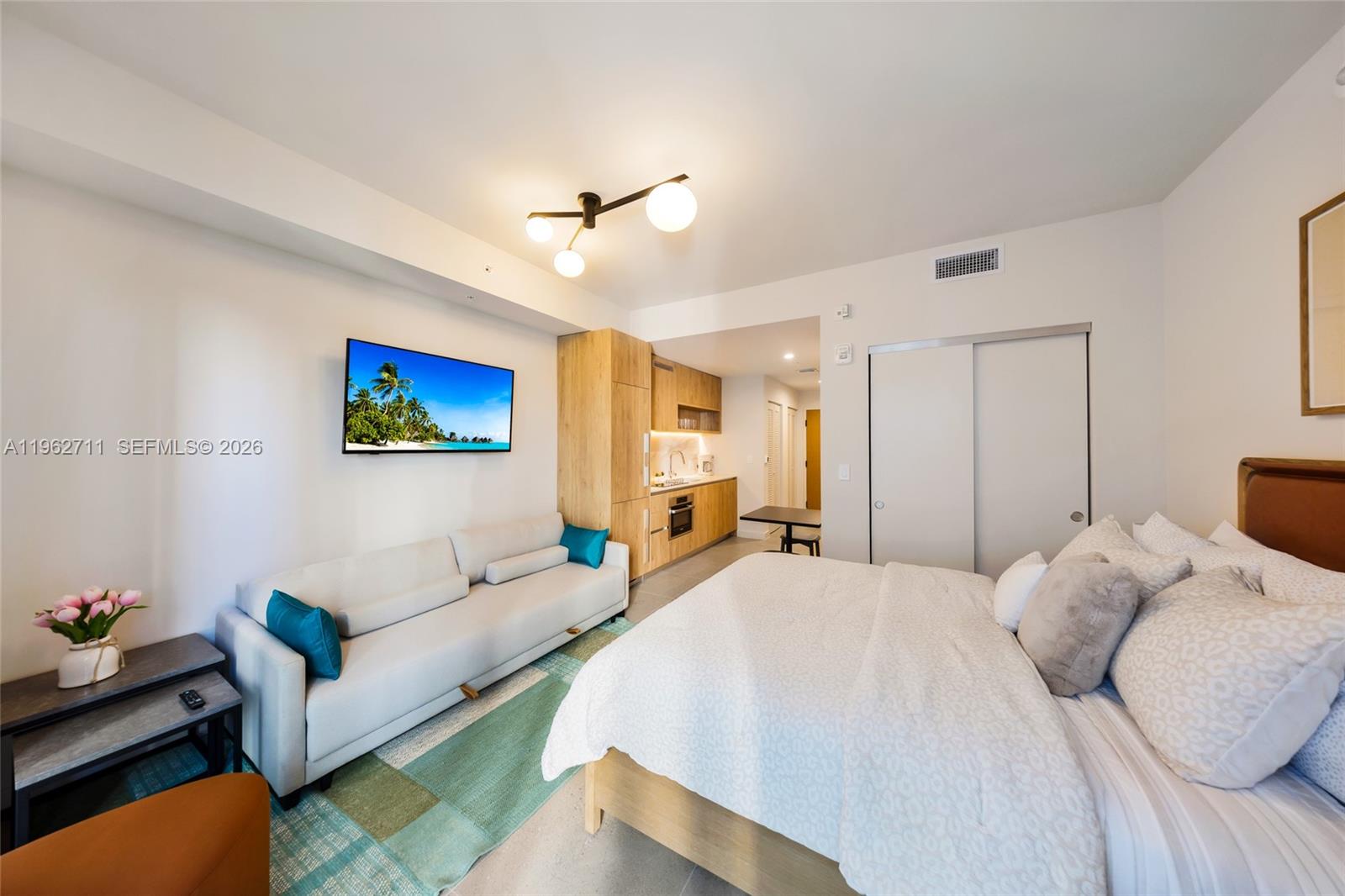 A studio apartment features a bed, a sofa, and a small kitchenette with wooden cabinets — 11 NE 6th St # 1208, Miami FL 33132, MIAMI, FL