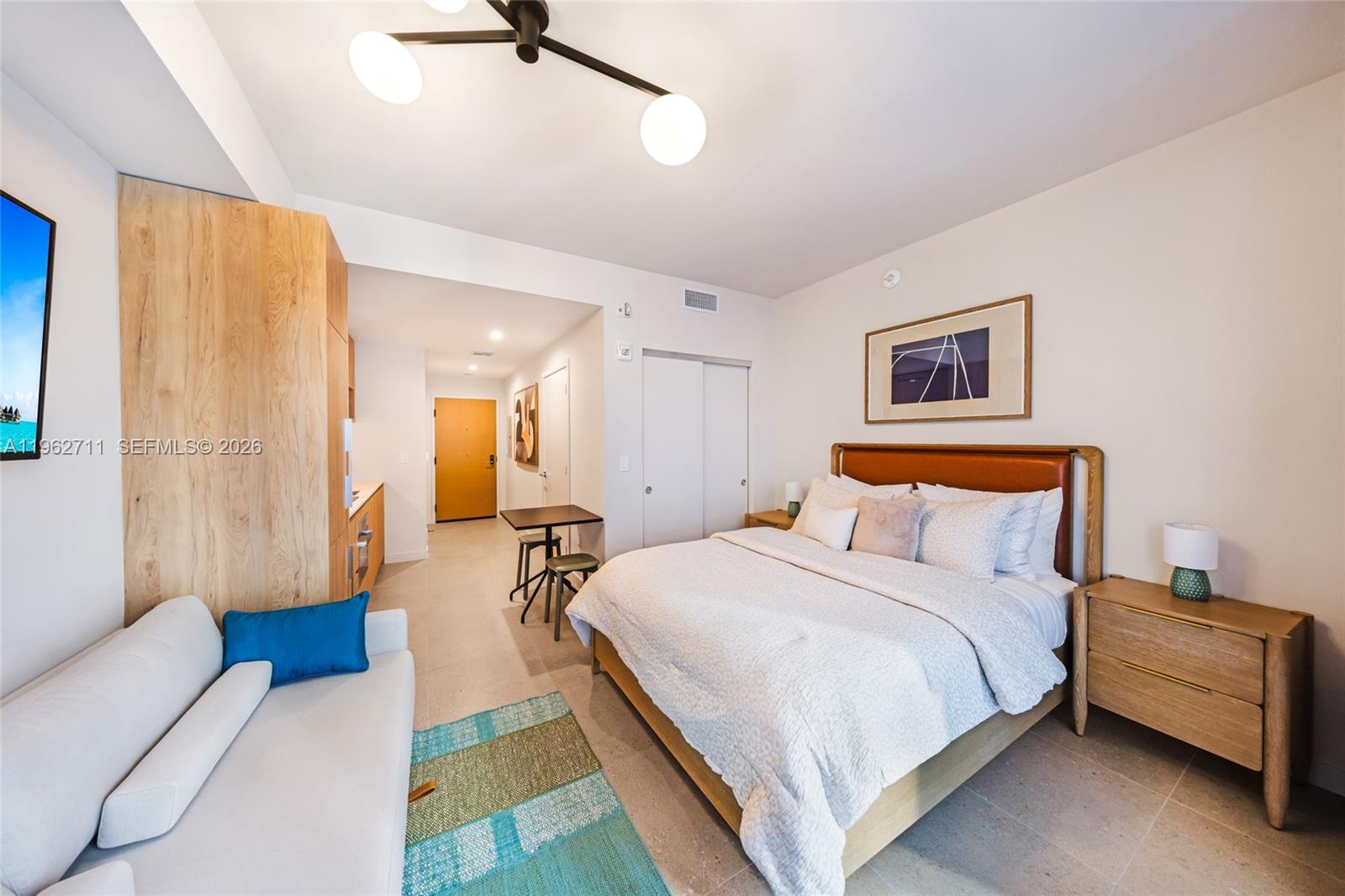 A studio apartment features a bed, a sofa, a small dining table, and light wood cabinetry — 11 NE 6th St # 1208, Miami FL 33132, MIAMI, FL