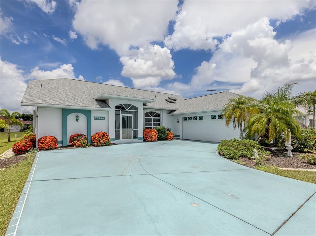 A single-story house with a blue driveway, white stucco walls, and a two-car garage — 25244 RAMPART BOULEVARD, PUNTA GORDA, FL